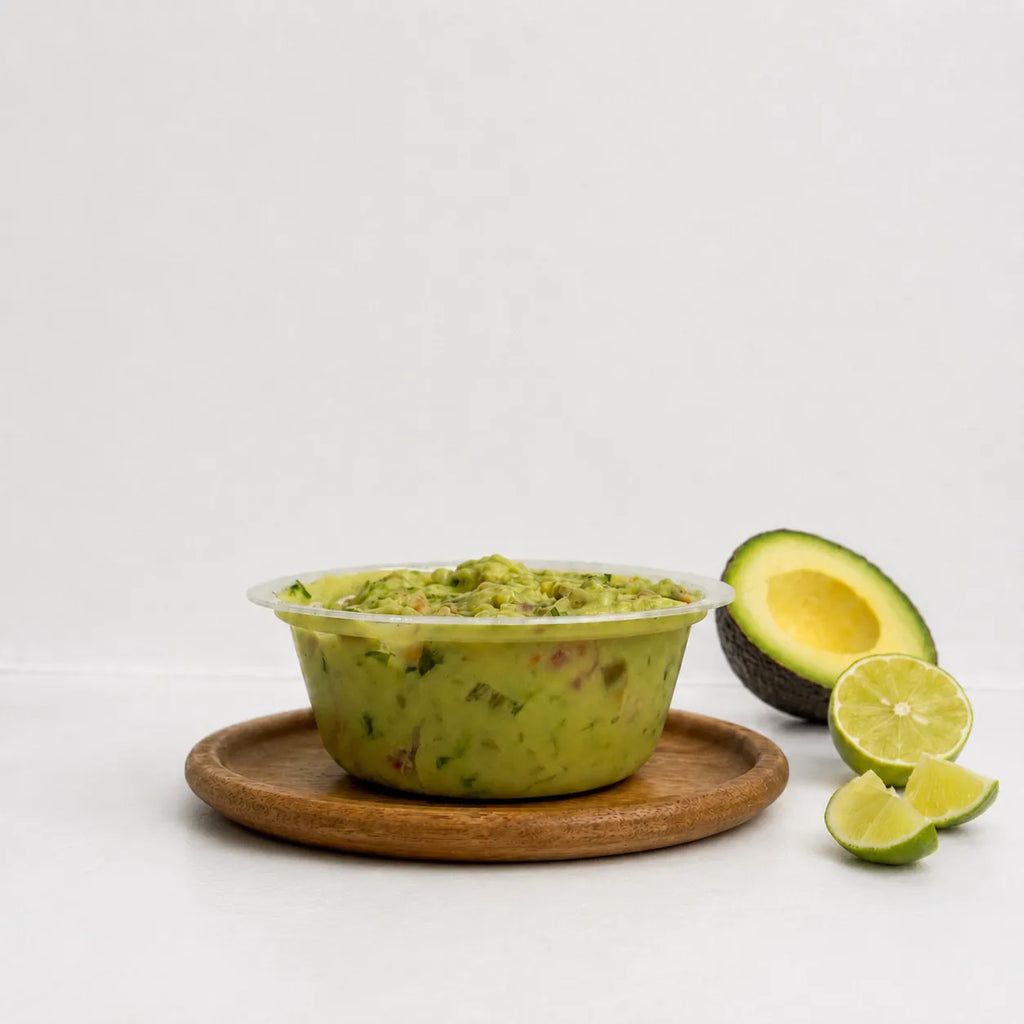 Open tub of The OG Guacamole on a wooden board